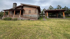 Una casa de piedra rústica con un porche de madera y un pabellón cubierto.