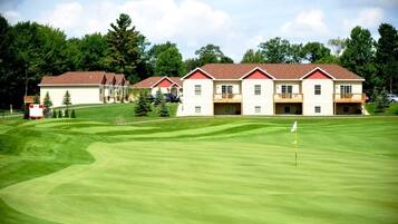 A golf course with a clubhouse featuring multiple buildings with red roofs and balconies.