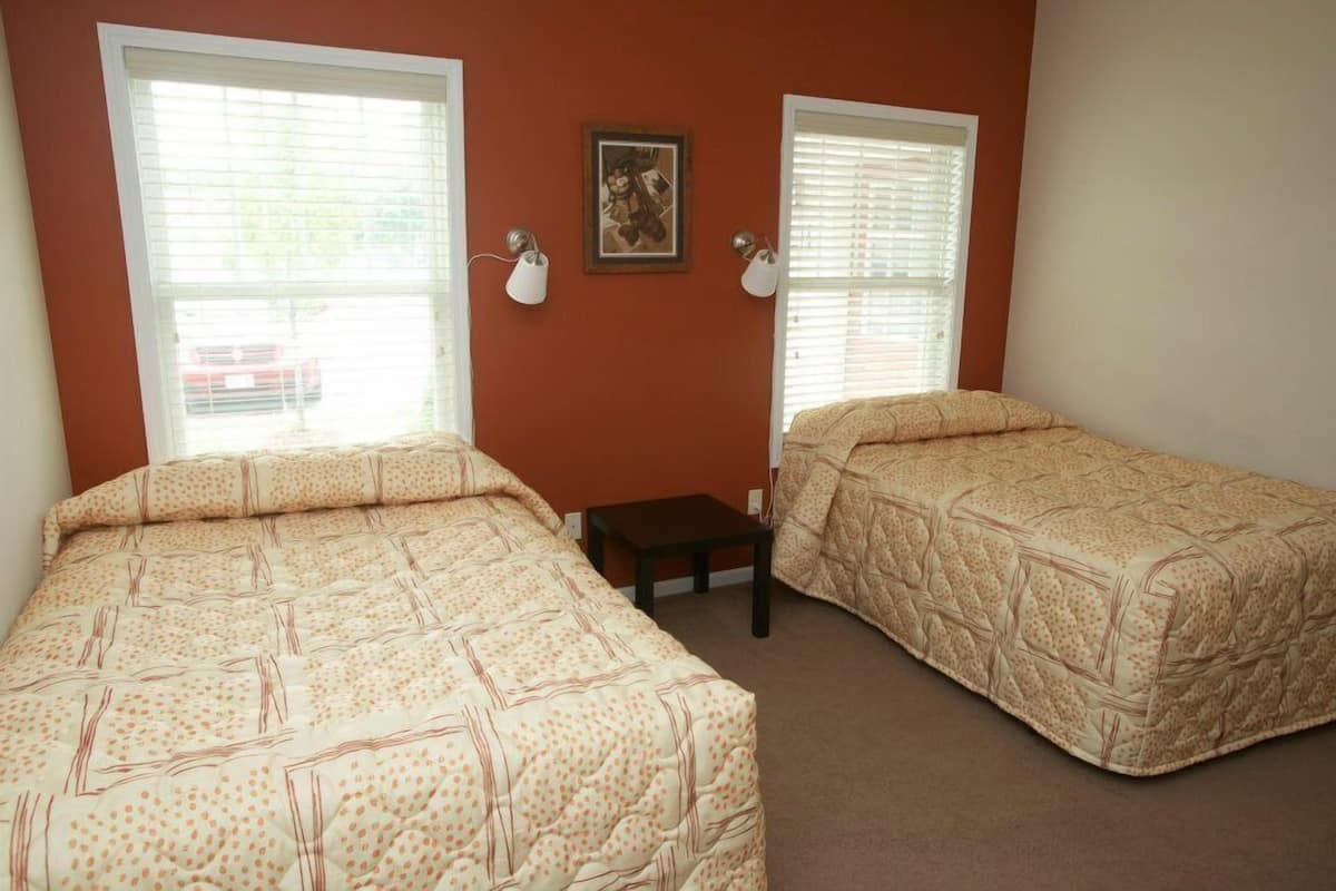 A bedroom with two beds, a small table, and a framed picture on the wall.