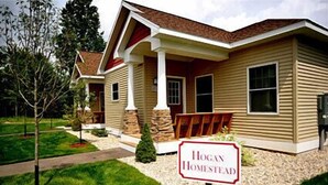 A two-story house with a front porch, stone pillars, and a sign that reads "Hogan Homestead." - The Loon (Gaylord)