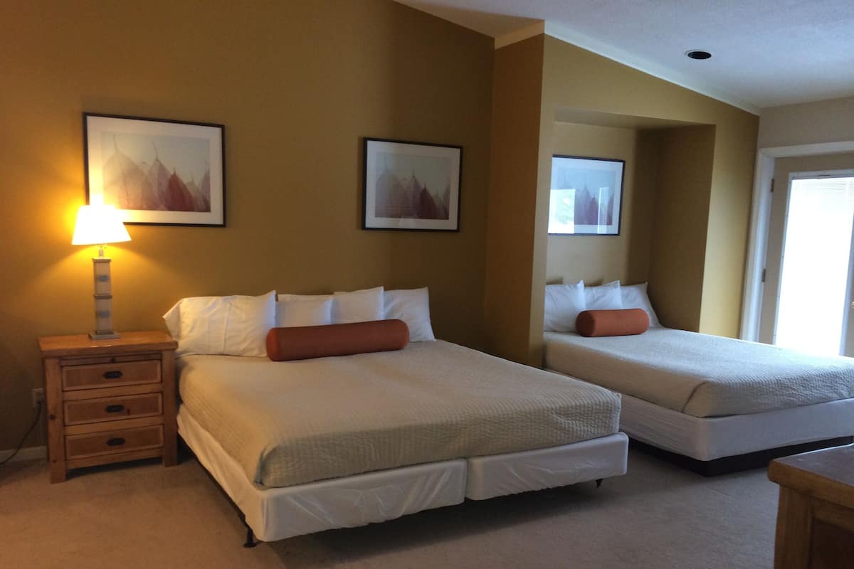 A hotel room with two beds, a nightstand with a lamp, and two framed pictures on the wall.
