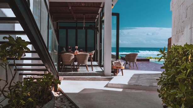 Área de estar ao ar livre com móveis de vime e vista para o mar.