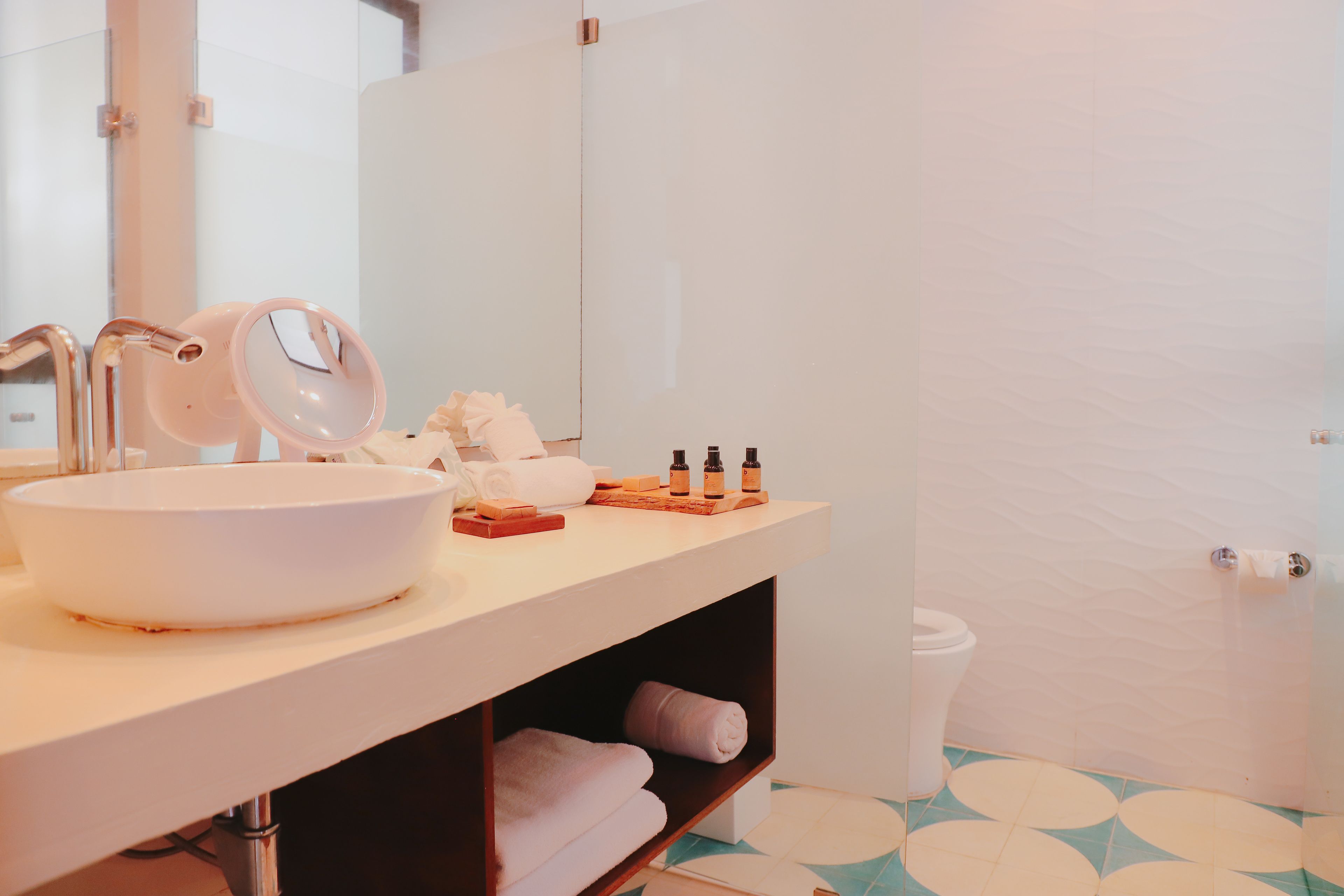 A bathroom with a white sink, mirror, and toiletries.