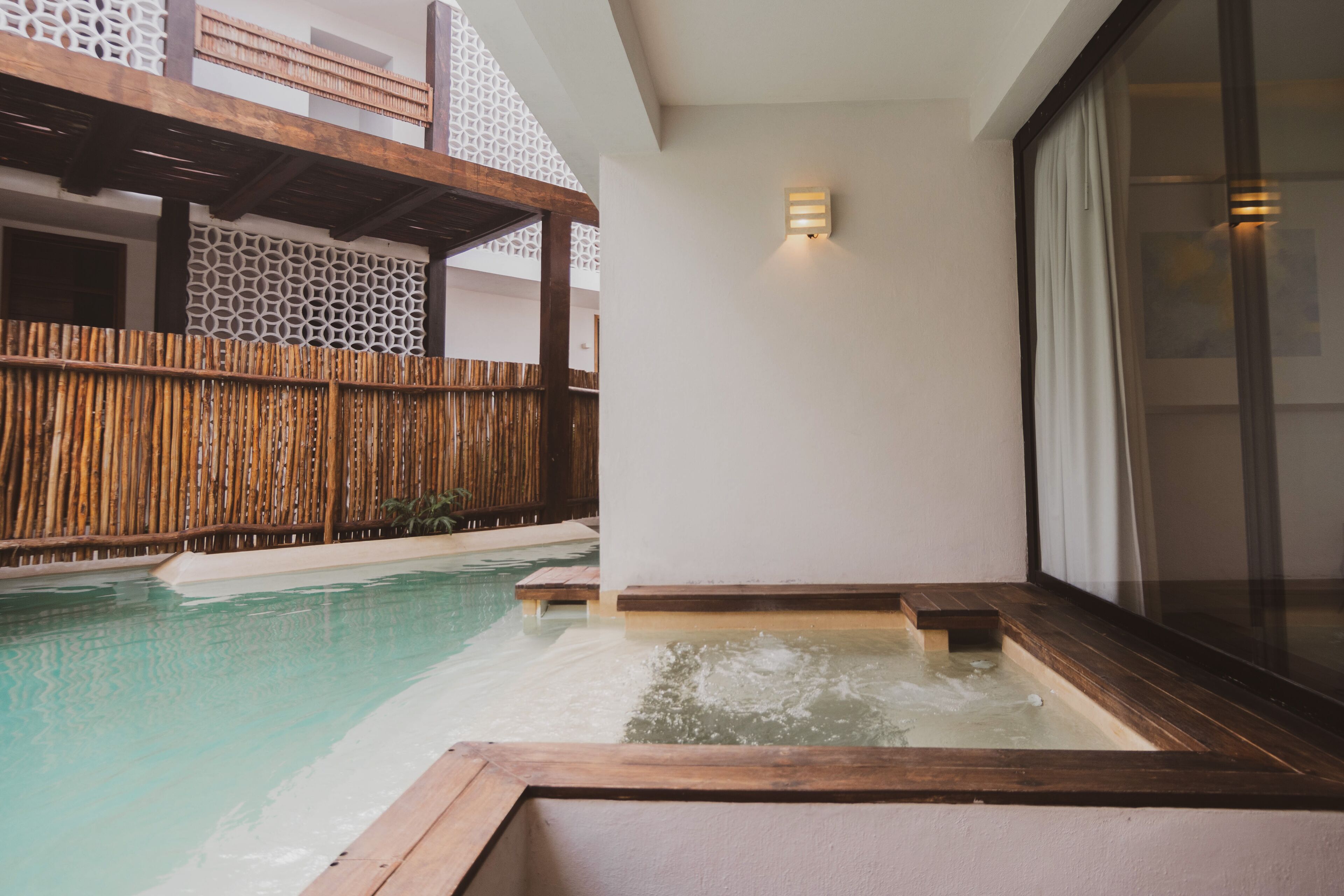 Een wellnessruimte met een jacuzzi, een houten terras en een bamboombekeuring.