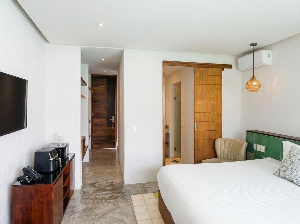A hotel room with a bed, a TV, a coffee maker, and a wooden wardrobe.