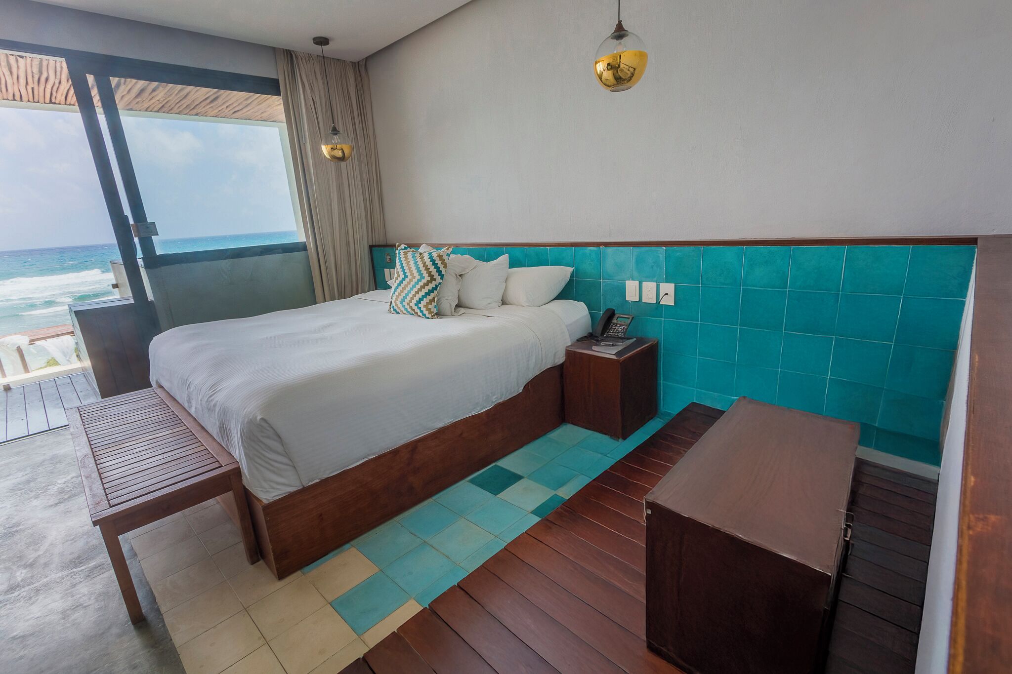 A bedroom with a bed, bedside table, and a view of the ocean.