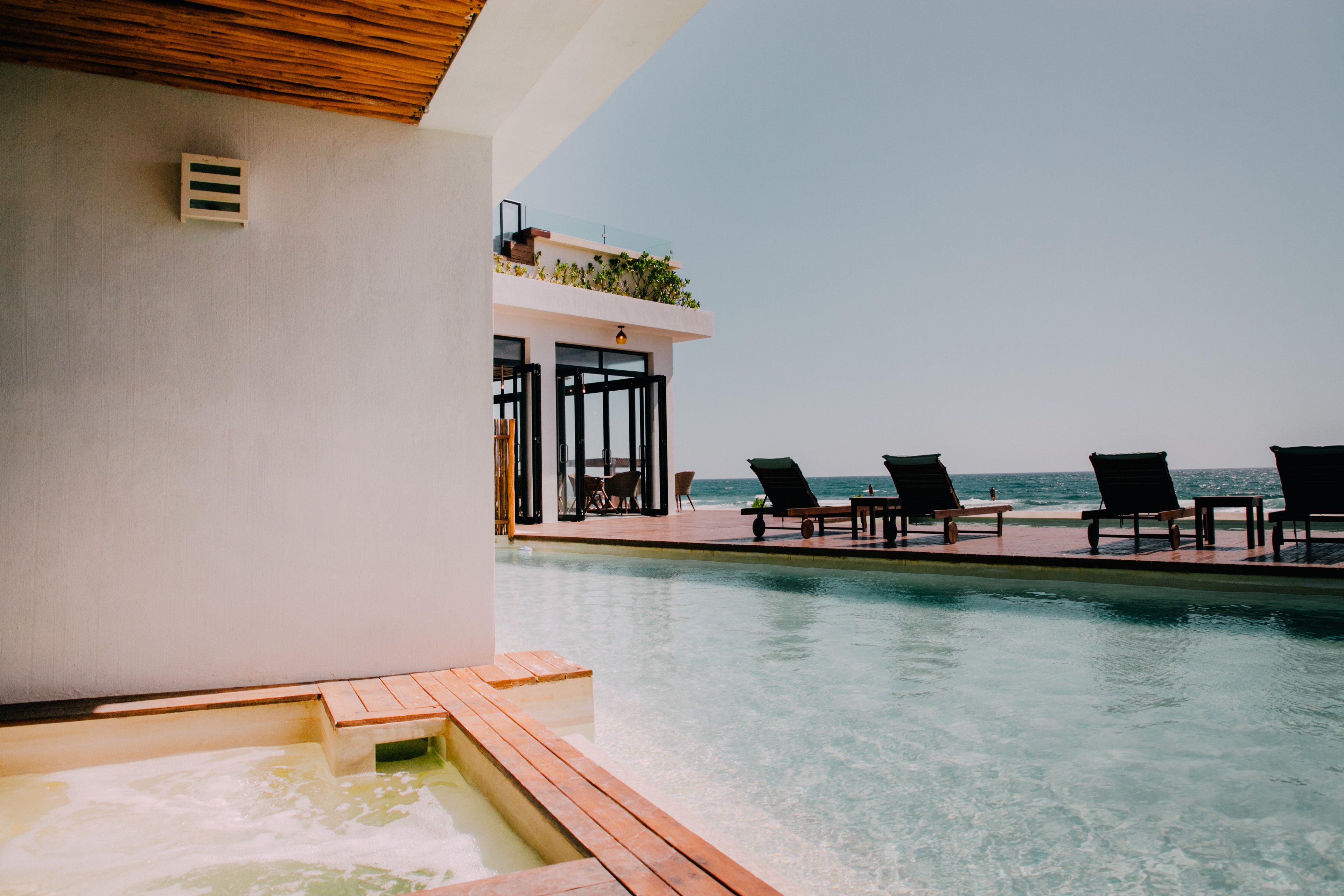 Área da piscina com espreguiçadeiras e vista para o mar.