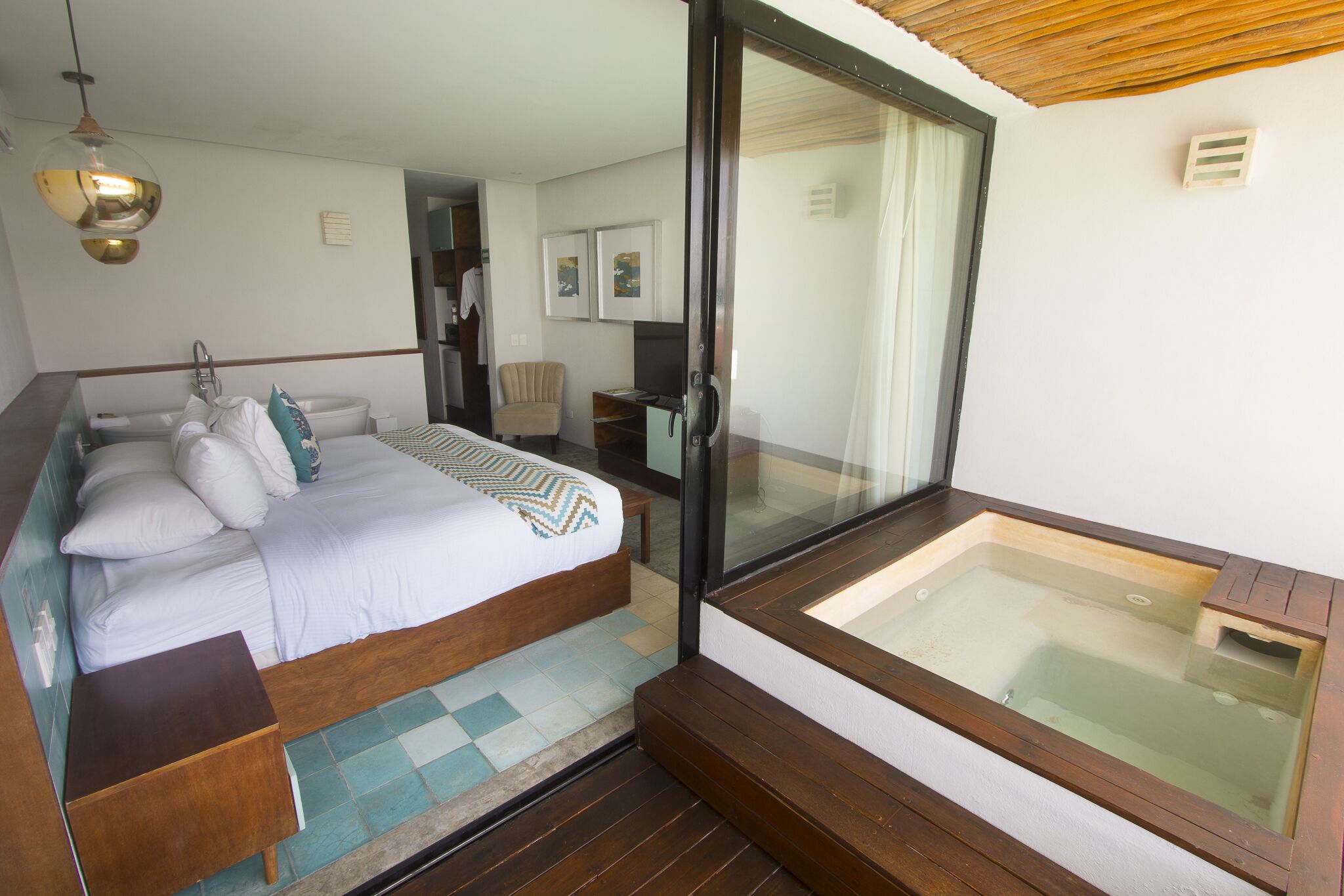 Een slaapkamer met een groot bed, een hottub in glazen ruimte en een houten plafond.