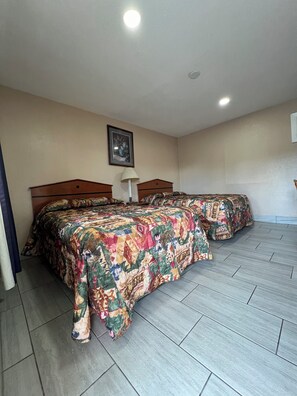 A hotel room with two beds, a ceiling light, a framed picture on the wall, and a tiled floor. - Budget Inn (Ocala)