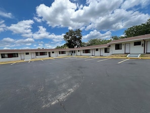 A row of motel rooms with a parking lot in front. - Budget Inn (Ocala)