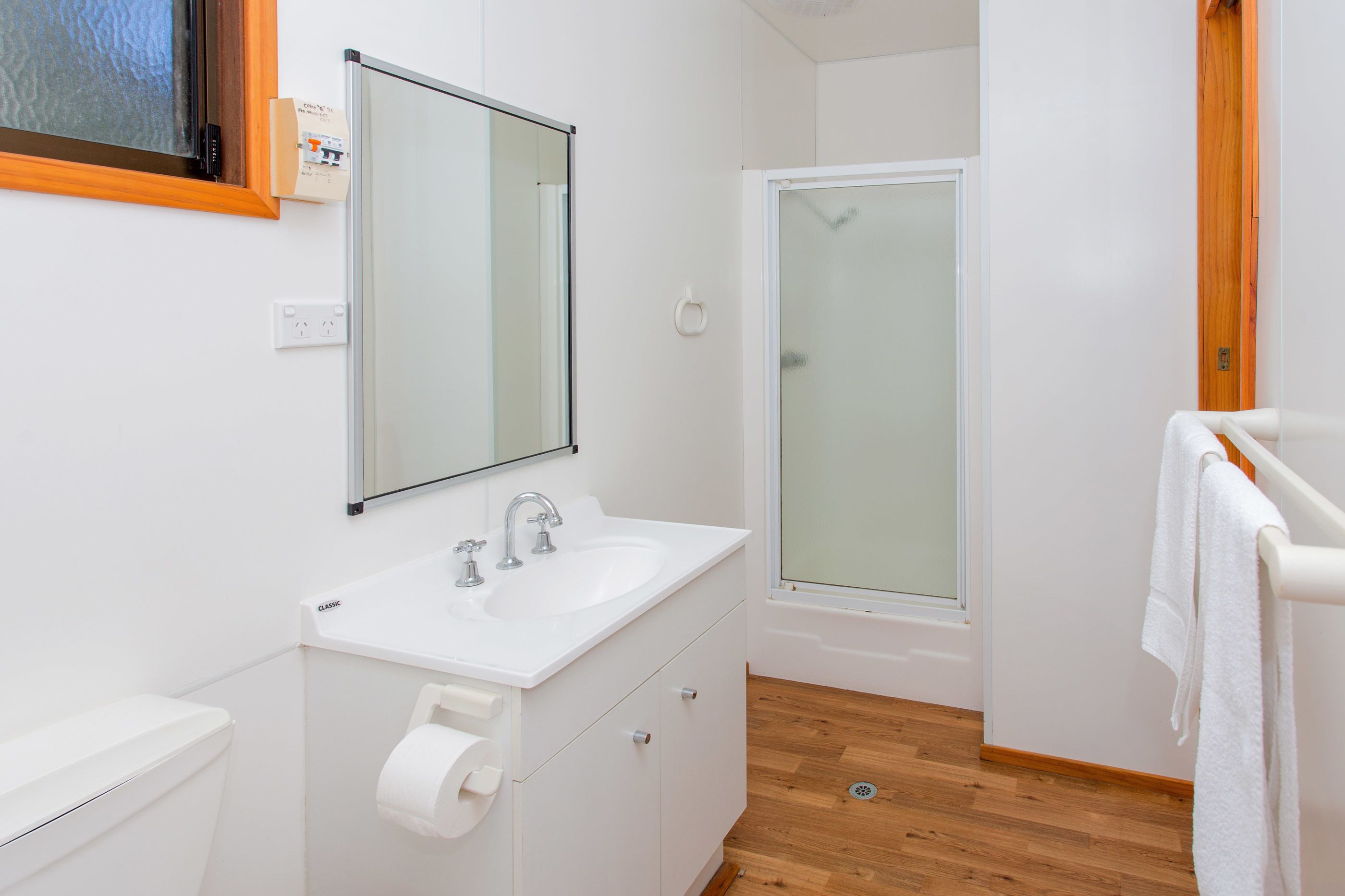 Un baño moderno con lavamanos, espejo y ducha blancos.