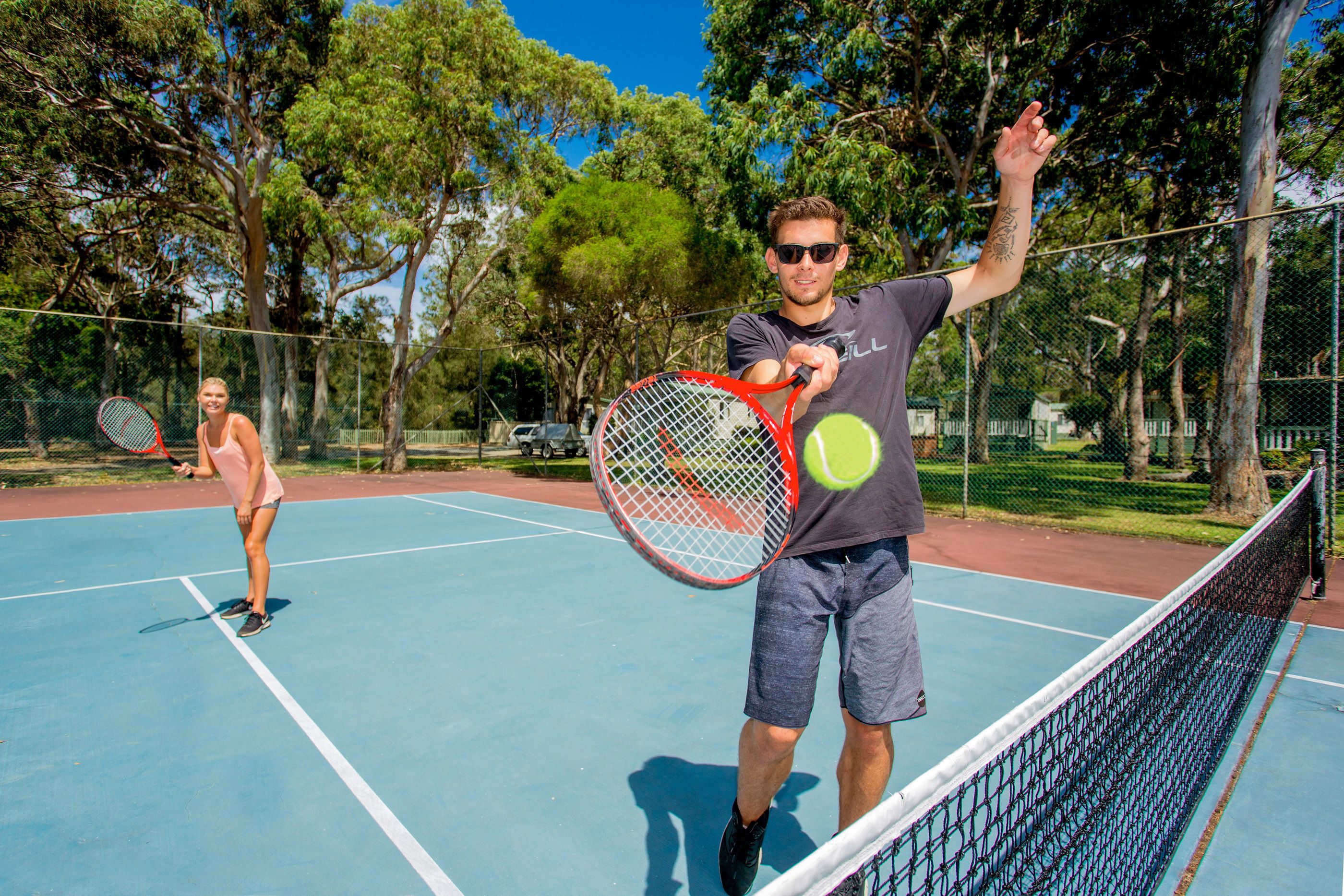 A tennis court with a net in the middle, surrounded by trees.