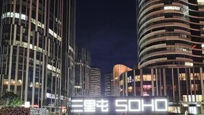 Ein modernes Gebäude mit beleuchteter Beschilderung, das durch vertikale Linien und eine gewölbte Fassade gekennzeichnet ist.