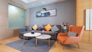 Ein modernes Wohnzimmer mit grauem Sofa, orangefarbenem Sessel und einem weißen Couchtisch.