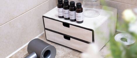 Un tocador de baño con un mueble de madera, un secador de pelo y tres botellas de gel de ducha.
