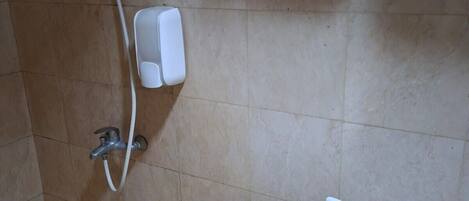 A shower area with a handheld showerhead, a wall-mounted soap dispenser, and a toilet paper holder.