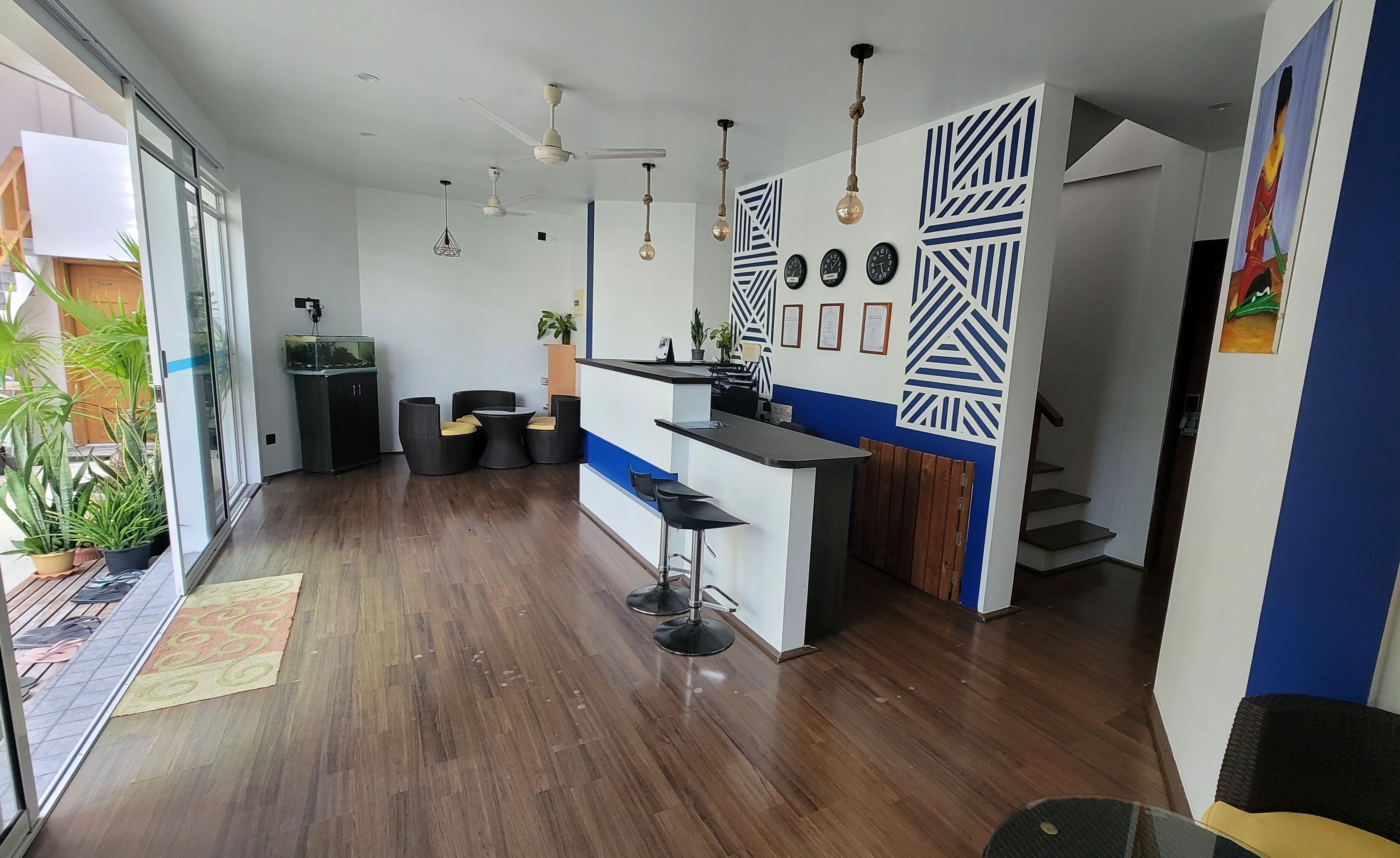 Une cuisine moderne dotée d’un bar, de planchers en bois et de ventilateurs de plafond.