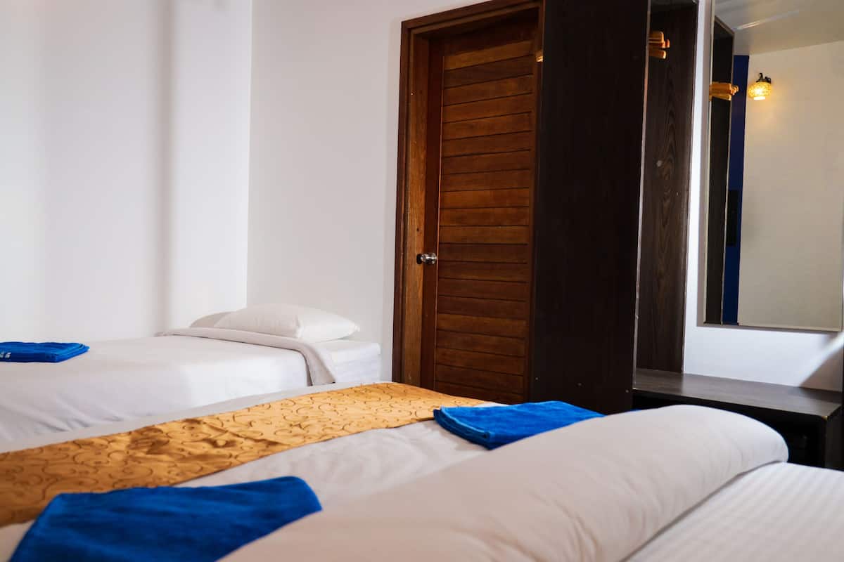 A hotel room with two beds, a wooden door, and a mirror.