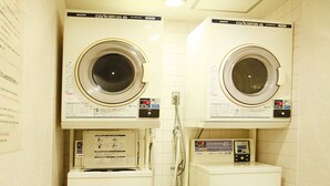A laundry room with two washing machines, a small stool, and a trash bin. - Asakusa Central Hotel (Tokyo)