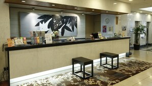 A reception area with a counter, two stools, a large abstract painting, and a potted plant. - Asakusa Central Hotel (Tokyo)