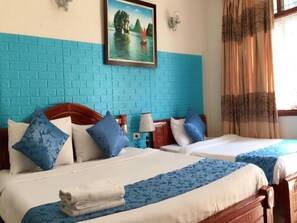 A hotel room with two beds, a blue brick wall, a painting of a lake, a lamp, and a window with curtains. - Hanoi Pearl Hostel (Hanoi)