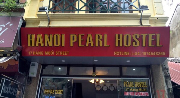 Hanoi Pearl Hostel's exterior with a red signboard, address, and hotline number.