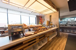 A buffet setup with a coffee machine, various food items, and a decorative plant.