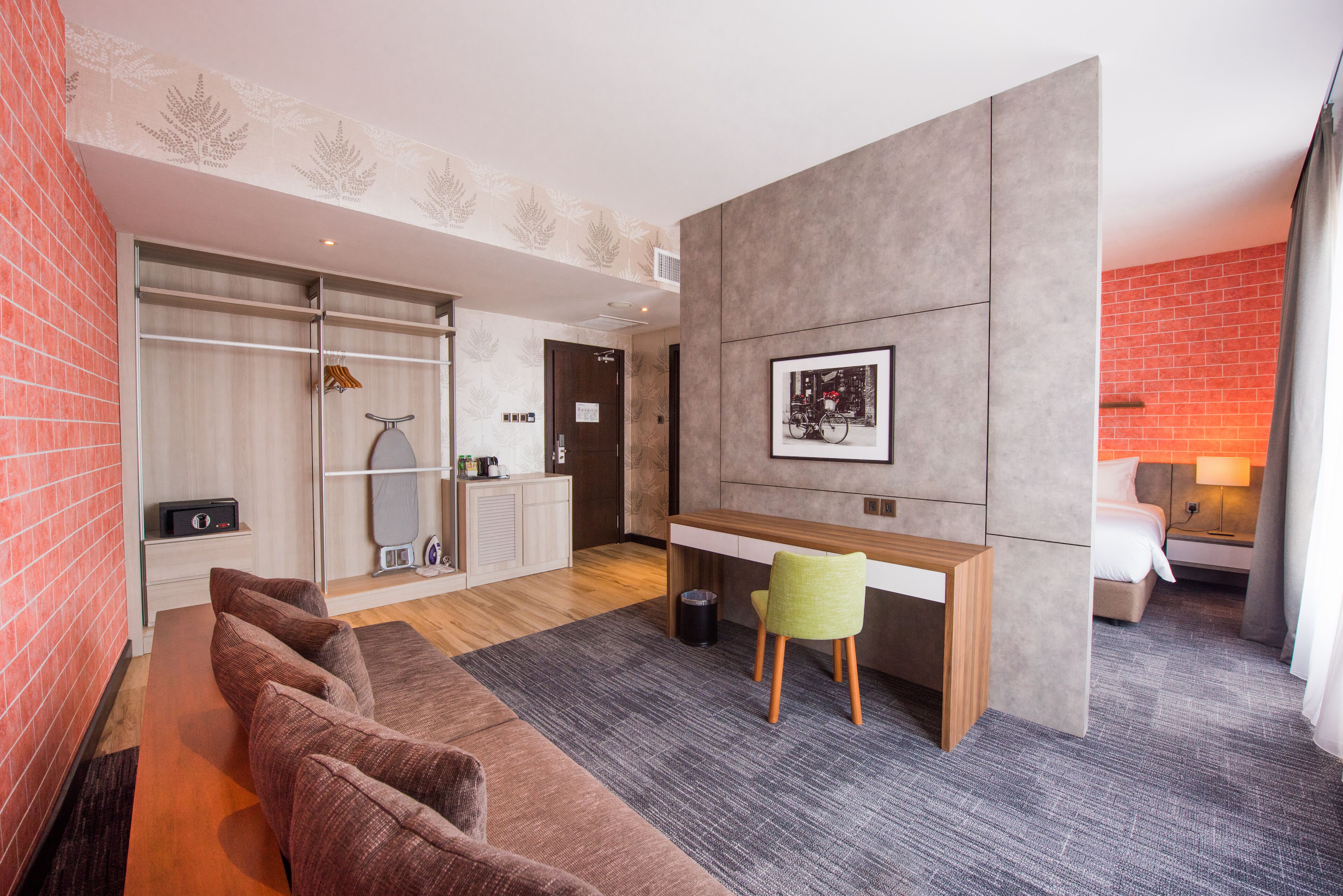 Een moderne hotelkamer met een bank, een bureau en een bed.