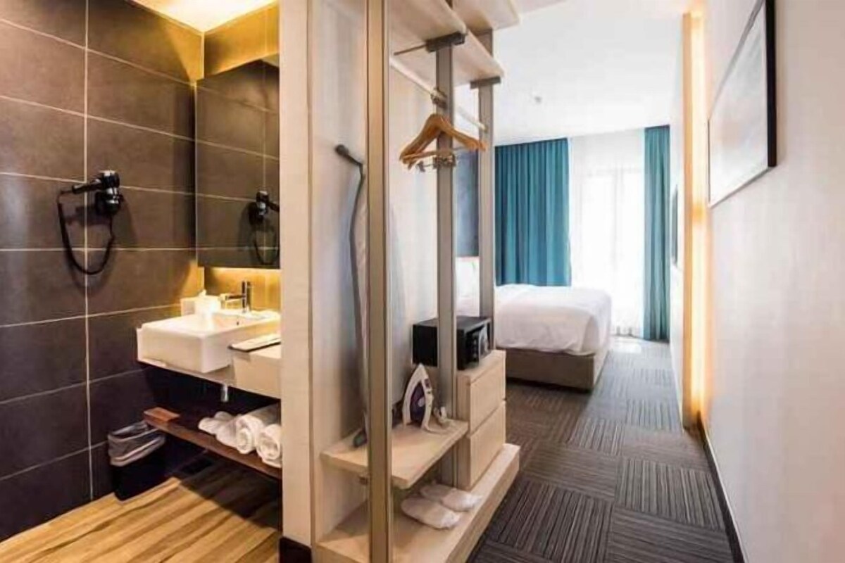 A modern hotel room with a shower, a sink, a bed, and a walk-in closet.