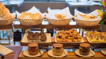 Ein Frühstücksbuffet mit verschiedenen Brotsorten, Gebäck, Muffins und Kaffee.
