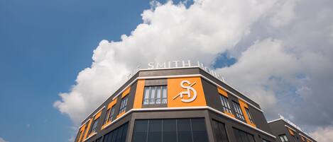 Een modern gebouw met een opvallend 'Smith' bord, grote ramen en een heldere lucht met wolken.