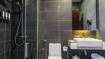 A modern bathroom with a glass-enclosed shower, a white toilet, and a wooden vanity with a sink and mirror.
