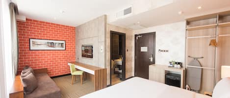 Habitación de hotel con cama, escritorio, silla, baño pequeño y armario.