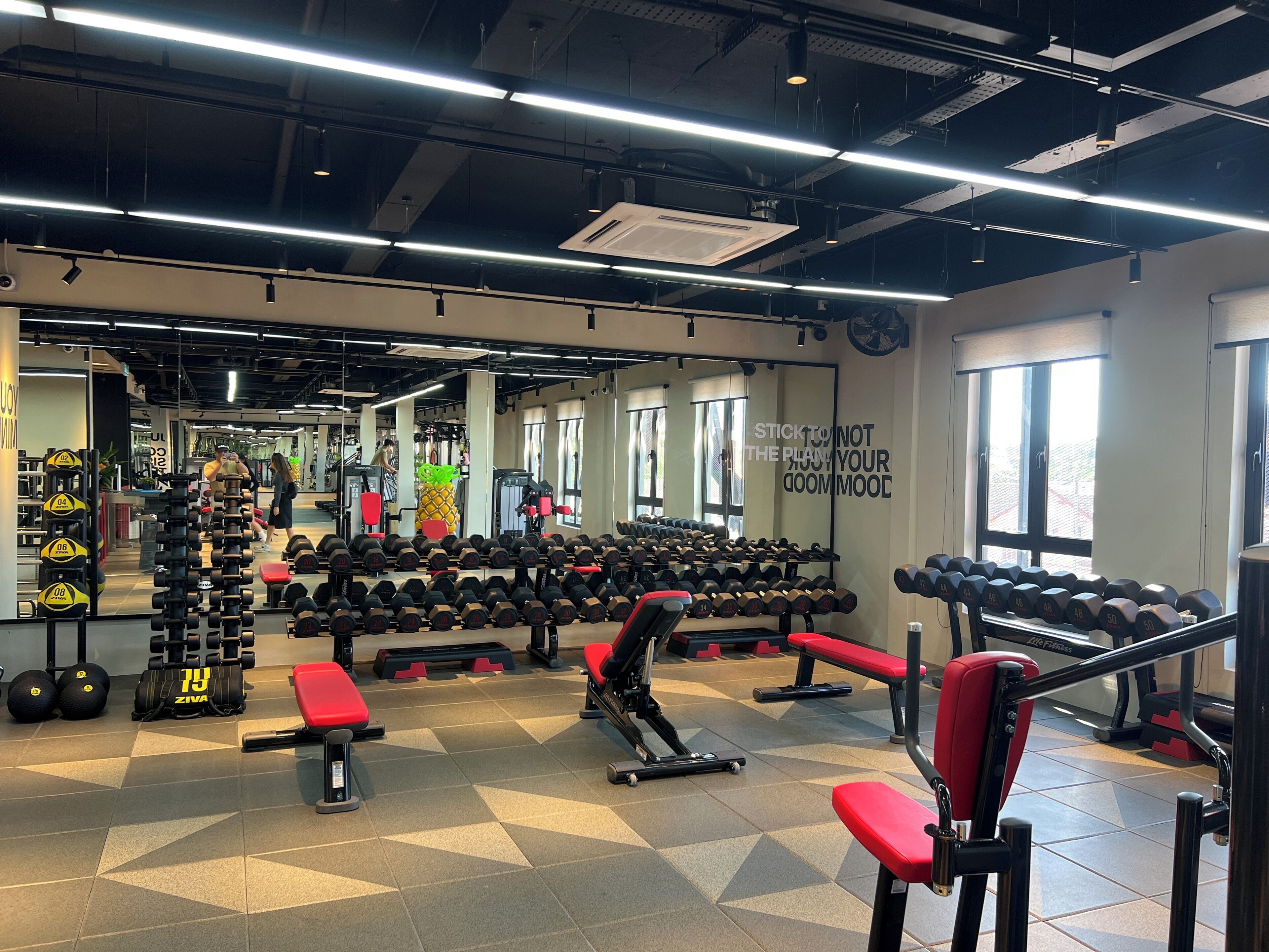 A gym with various weightlifting equipment, a mirrored wall, and motivational text.