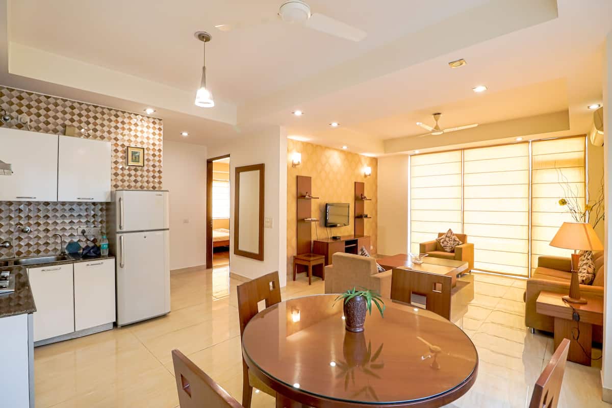 A modern kitchen with white cabinets, a refrigerator, and a dining area with a round table and chairs.