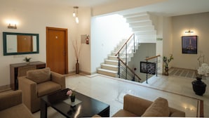 Un vestíbulo de hotel con una escalera, sofás, una mesa de centro y un espejo.