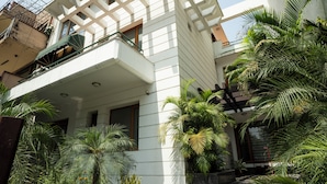 Un edificio moderno con balcón, rodeado de vegetación exuberante y palmeras.
