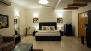 Un dormitorio moderno con una cama grande, mesitas de noche, un ventilador de techo y obras de arte en las paredes.