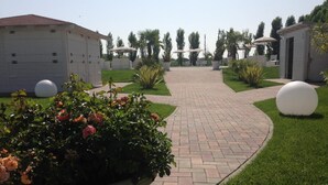 A pathway leading to a building with a tiled roof, surrounded by well-maintained grass and potted plants. - Hotel Bussana (Porto Tolle)