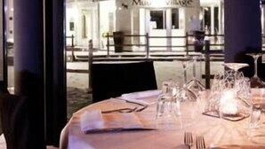 A dining table set for two with a view of a building labeled "Moulin Village" through a window. - Muu Village (Folgaria)