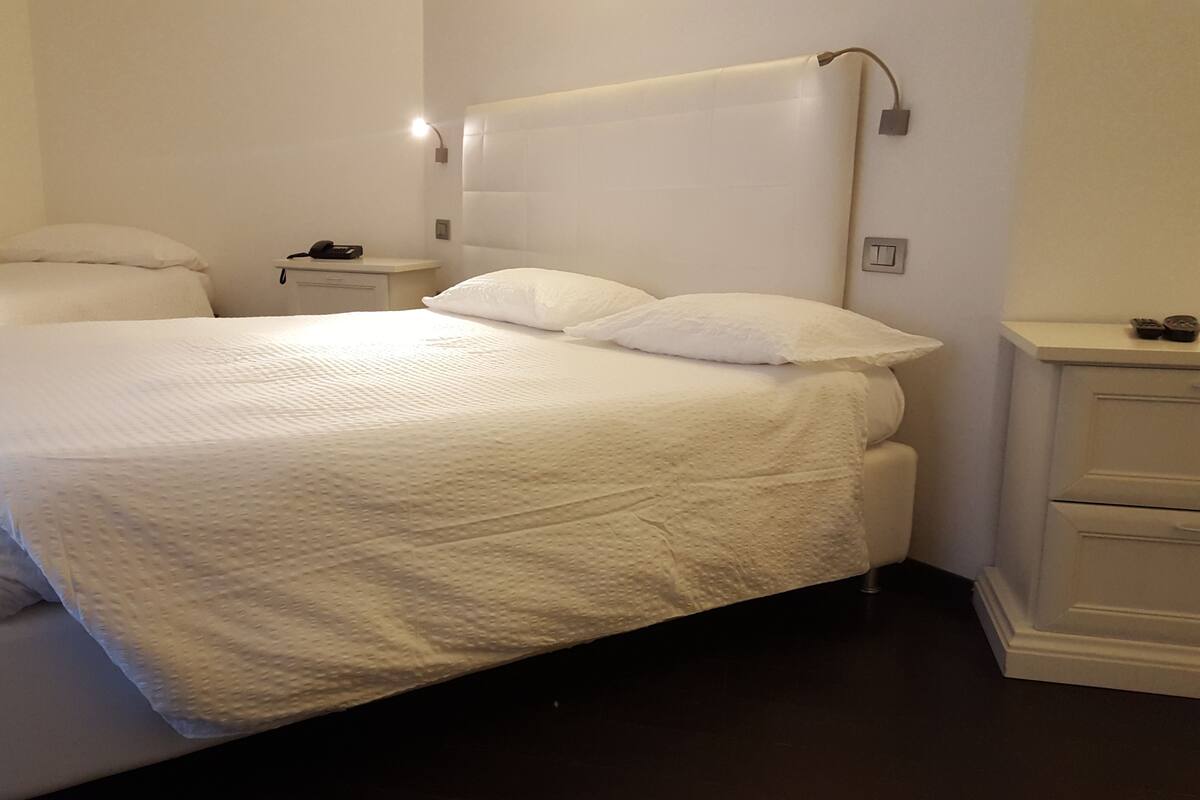 A bedroom with a large bed, bedside tables, and a nightstand.