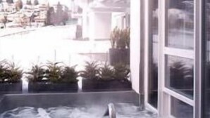 A modern building with a glass facade, a hot tub area, and a view of a snowy landscape. - Muu Village (Folgaria)