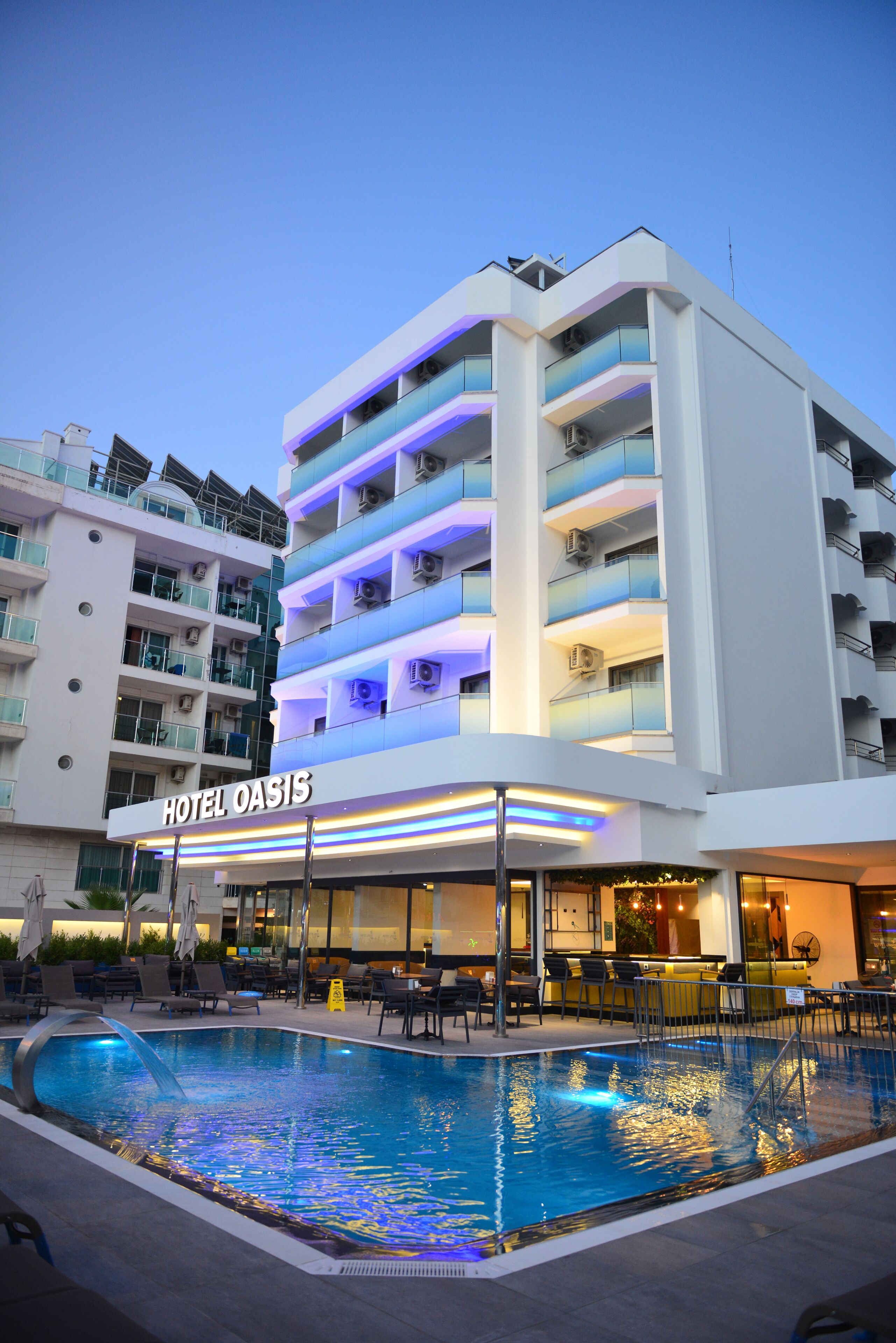 A hotel with a pool area, multiple balconies, and a sign reading "HOTEL OASIS".