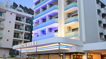 A hotel with a pool area, multiple balconies, and a sign reading "HOTEL OASIS".