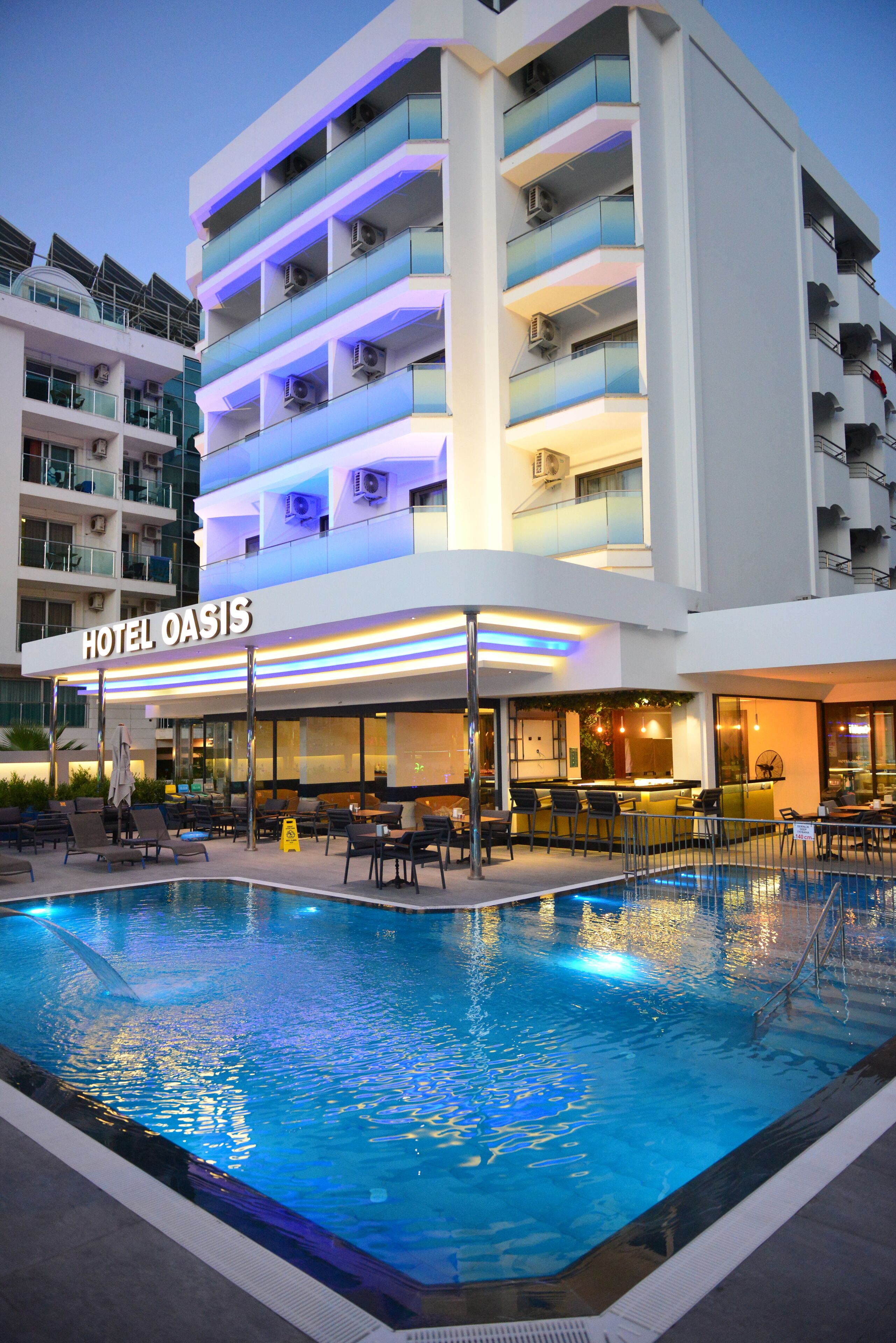 Un hotel con zona de piscina, varios balcones y una zona de bar y salón.