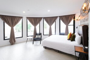 Una habitación de hotel moderna con una cama grande, una silla y un escritorio.