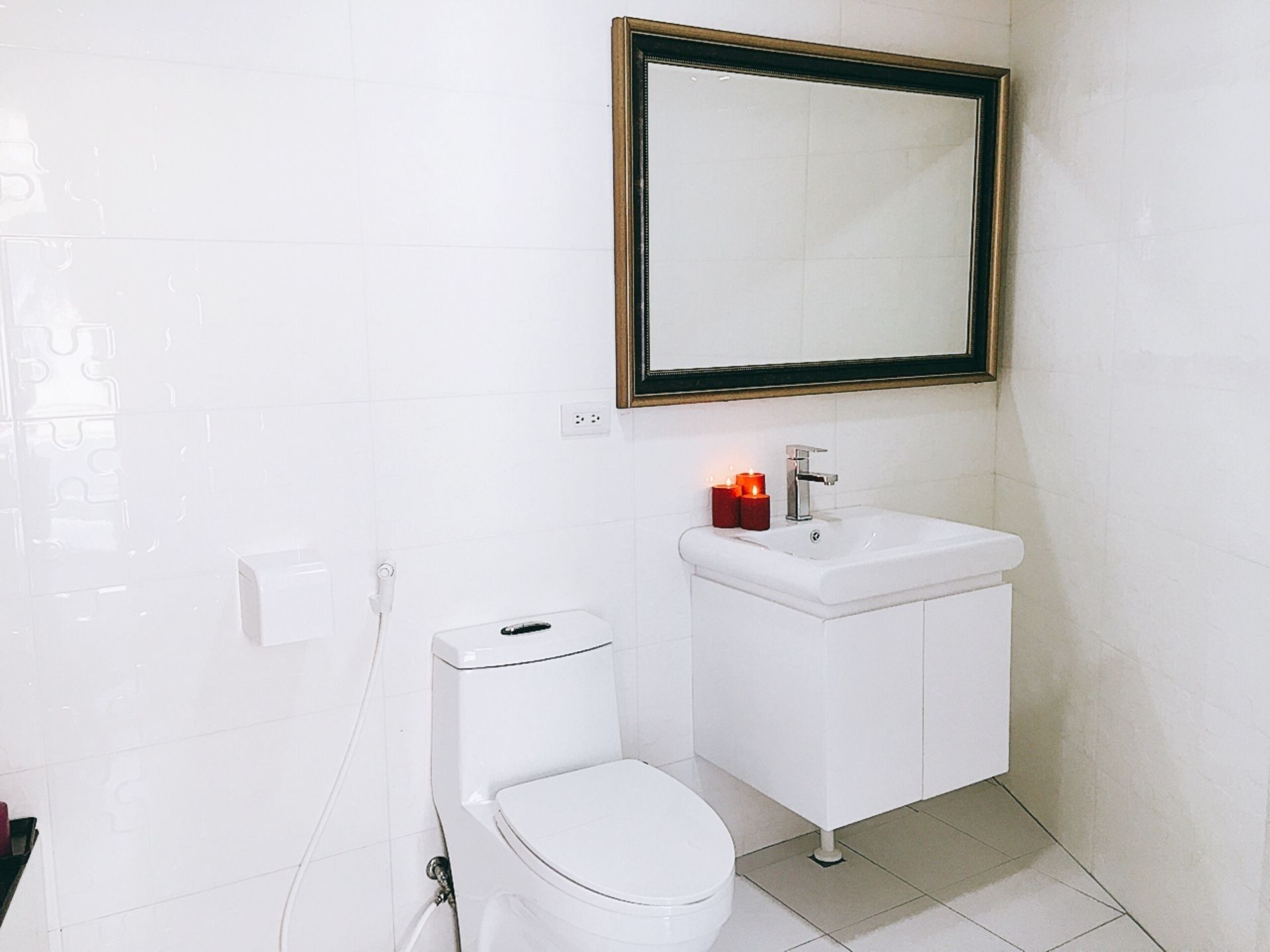 Un baño blanco con inodoro, lavamanos y espejo.