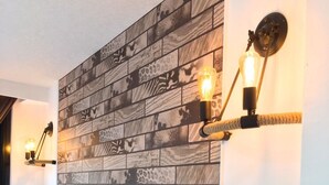 A room with a leather sofa, a patterned wall, and two wall-mounted light fixtures. - Live in the happiness (Zhushan)