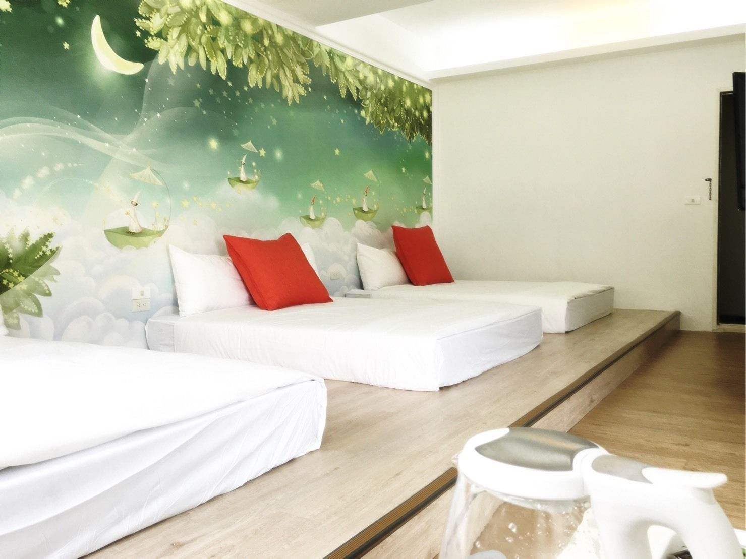 A hotel room with two beds, a mural with a nature theme, and a small seating area with a table and chairs.