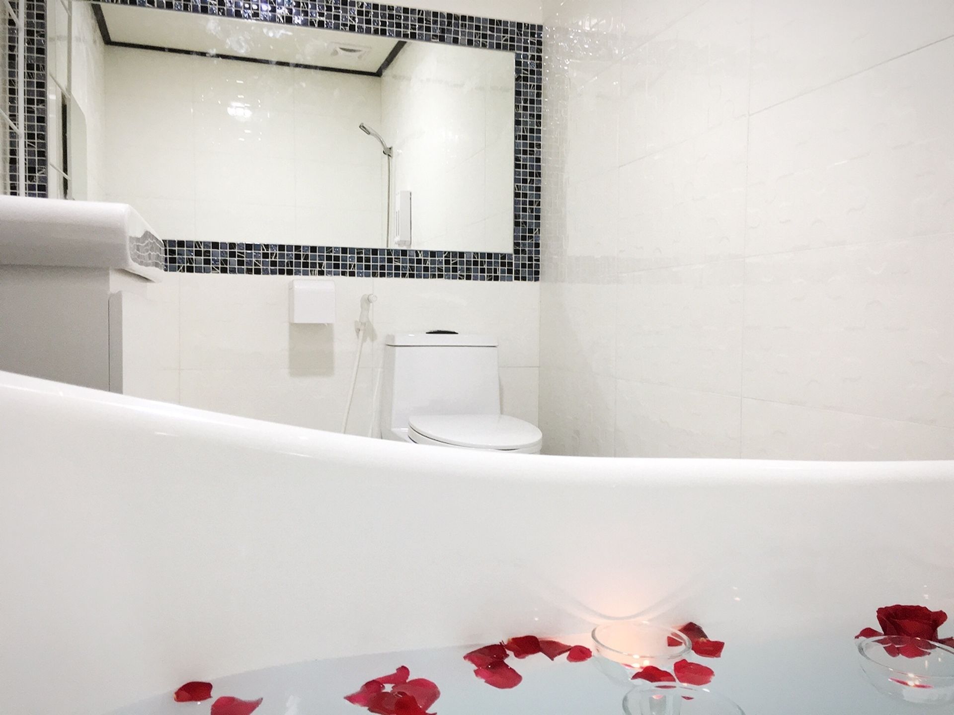 A modern bathroom with a freestanding bathtub, a toilet, and a mirror above the sink.